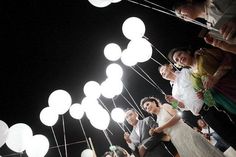 a group of people standing next to each other in front of white balloons and string lights