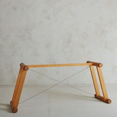 a wooden table with two legs and some wood sticks on the top, against a white wall