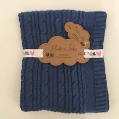 a blue knitted blanket with a tag attached to the front and back of it