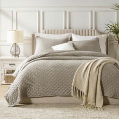 a bed with a white headboard and beige bedspread