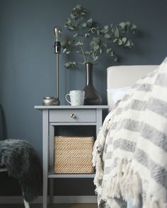 a bed room with a neatly made bed and a basket on the nightstand next to it