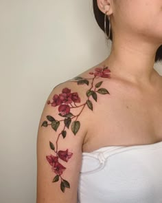 a woman's shoulder with red flowers and green leaves on her left upper arm