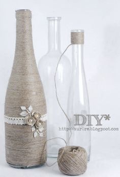 two glass bottles with twine on the top and one empty bottle next to it