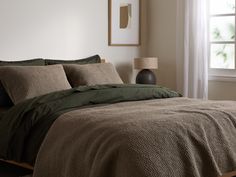 the bed is made up with green sheets and pillows