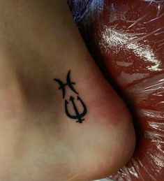 a small tattoo on the foot of a person with an anchor and cross in it