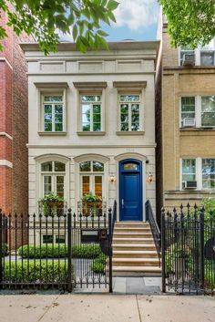 a blue door is on the front of a two - story brick house with wrought iron fence