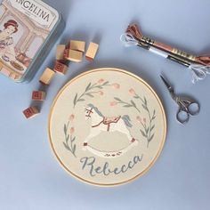 a cross stitch kit with wooden blocks, scissors and other crafting supplies on a table