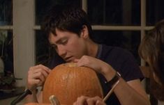 a man carving a pumpkin with a knife