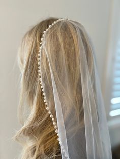 the back of a woman's head wearing a veil with pearls and beads on it