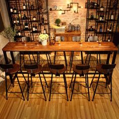 a wooden table surrounded by chairs and shelves with bottles on it in a wine cellar