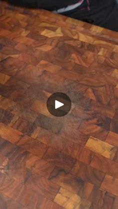 a close up of a wooden cutting board with a video playing button on it's side