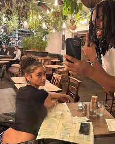 a woman taking a photo with her cell phone while sitting at a table in a restaurant