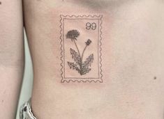 a stamp with a dandelion tattoo on the back of a woman's stomach