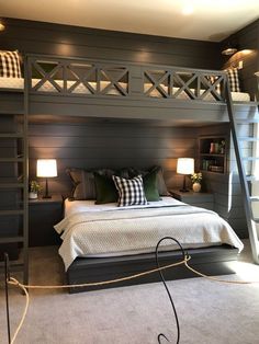 a bedroom with a loft bed and two lamps on either side of the bed, in front of a bookshelf