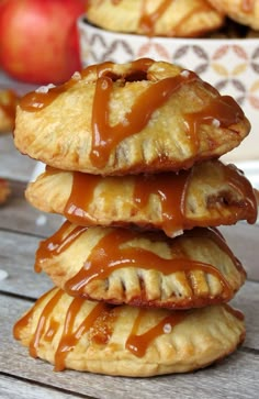 three apple turnovers stacked on top of each other with caramel drizzle