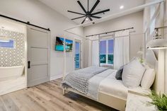 a bedroom with a bed, ceiling fan and two doors leading to the outside patio