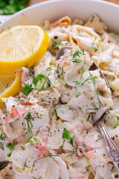 a close up of a bowl of food with lemon wedges and garnish