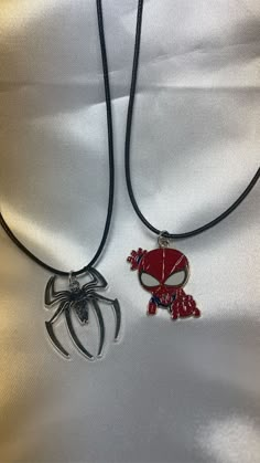 two spiderman necklaces on a black cord