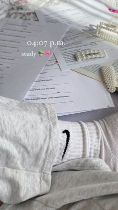 a person's feet in white socks on top of a bed next to papers and beads