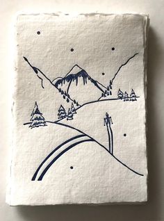 a white and blue painting on top of a wooden block with mountains in the background