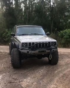 a jeep is parked in the dirt near some trees