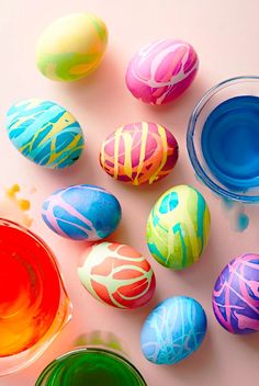 colorful painted eggs sitting next to each other on a white surface with blue and yellow paint