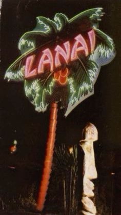 a white fire hydrant sitting next to a neon sign that says lanai on it