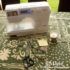 a sewing machine sitting on top of a table next to some scissors and tape dispenser