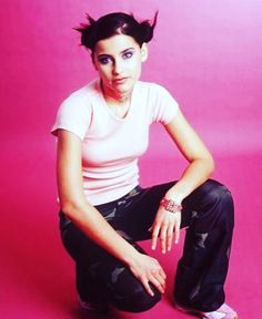 a woman sitting on the ground in front of a pink background