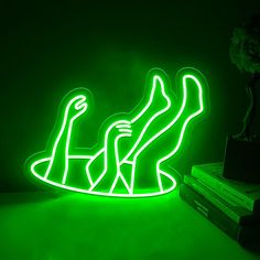 a green neon sign sitting on top of a table next to a stack of books