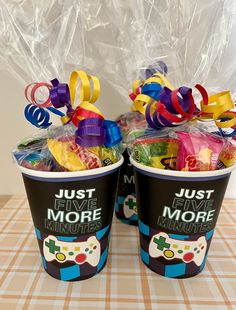 two cups filled with candy and bows on top of a table