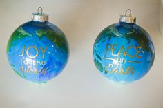 two christmas ornaments with the words peace and earth painted on each ornament,