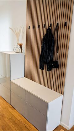 a coat rack with two coats hanging on it's sides and a bench in the foreground