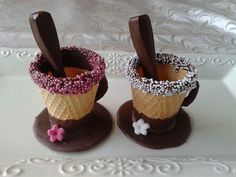 two ice cream cones decorated with chocolate and sprinkles