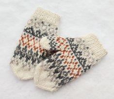 two knitted mittens sitting on top of snow covered ground next to each other