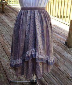 The brown calico prairie skirt is in nice 1970's-1980's vintage condition.  I didn't find any stains or tears.  It has rusty red, teal, white, purple and green flowers and leaves on the brown to light beige background.  There is also a geometric design alternating between the floral areas.  It has an elastic waistband and a ruffle near the bottom.  I estimate the skirt to be a small to medium size but check measurements carefully.  The skirt has been recently laundered and comes from a smoke and pet free home.   Note: all measurements are taken laying flat and doubled where appropriate.  Label - none Fabric - cotton or cotton/polyester blend  Color -  beige, brown, rusty red, teal, white, purple, green Tag Size - none but estimate sm to med  Waist - 24 in. unstretched and stretches to abou Purple And Green Flowers, Prairie Skirt, Purple And Green, Beige Background, 1980s Vintage, Beige Brown, Green Flowers, Flowers And Leaves, Purple Green