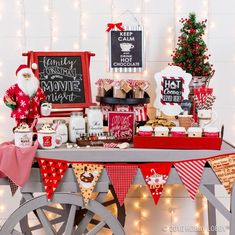 a christmas themed dessert table with santa clause decorations and candy bar wrapper bunting