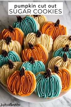 pumpkin cut out sugar cookies on a white plate with blue, orange and yellow frosting