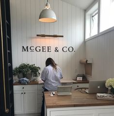 a woman standing at a desk with a laptop in front of her and the words mcgeee & co above it