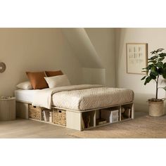 a bed with two storage drawers underneath it in a room next to a potted plant