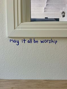 the words may it all be worship are written in blue ink on a white wall