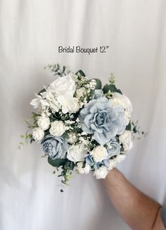 a bridal bouquet with white and blue flowers in the palm of someone's hand