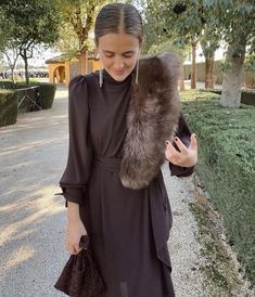 a woman is walking down the street with a fur stole around her neck