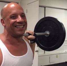 a man is smiling while holding a barbell