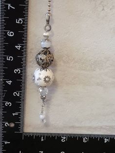 a white beaded necklace hanging from a ruler