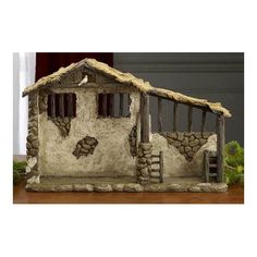 a small house made out of rocks and grass on a wooden table in front of a window