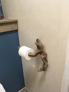 a toilet paper holder made out of driftwood is hanging on the wall in a bathroom