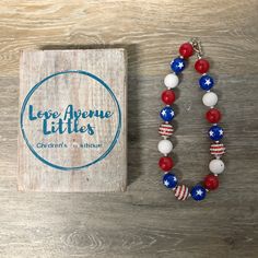 a red, white and blue beaded bracelet next to a book on a wooden table