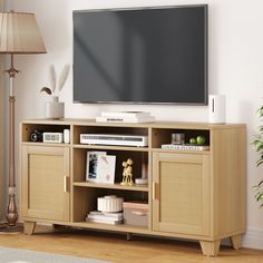 a flat screen tv sitting on top of a wooden entertainment center next to a lamp