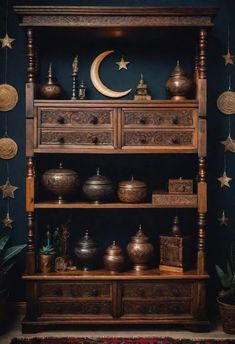 an old wooden shelf with pots and pans on it in a dark blue room